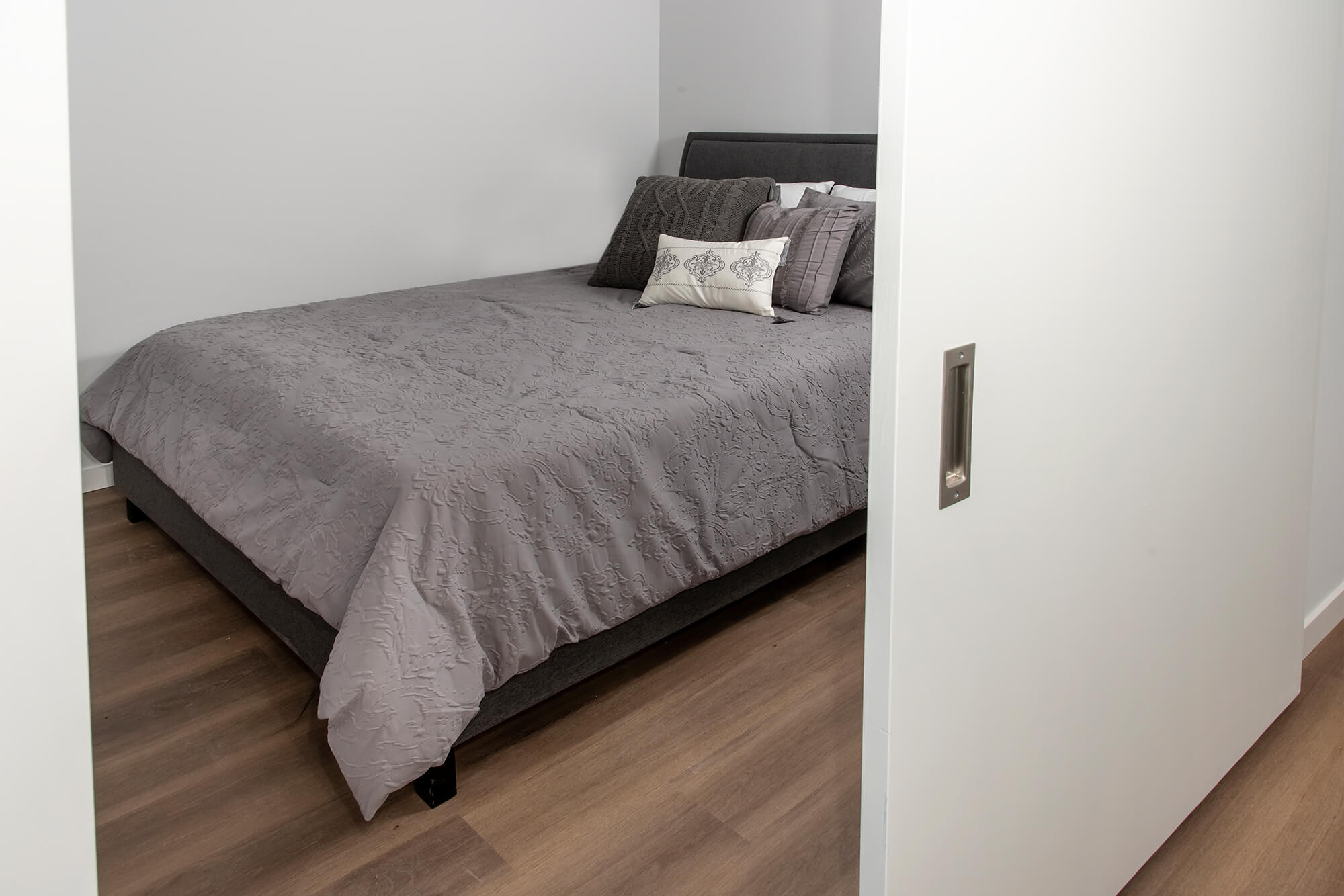 Bedroom with gray bedding and sliding door entry.