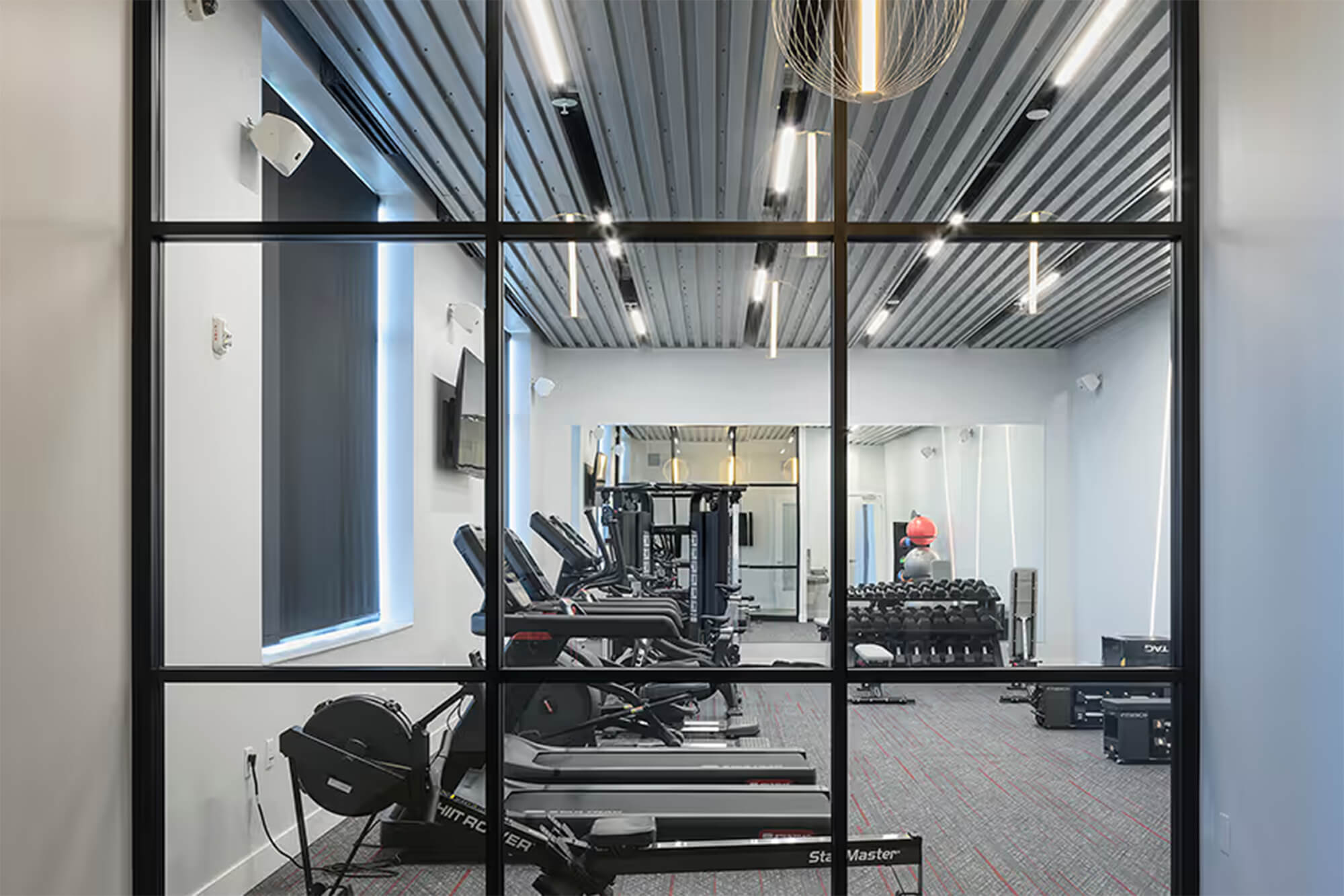 Fitness center with cardio machines, free weights, and mirrored wall