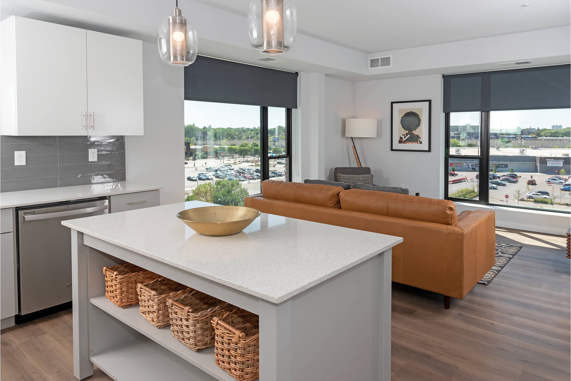 Kitchen and living area with a large island, pendant lighting, leather sofa, and expansive windows.