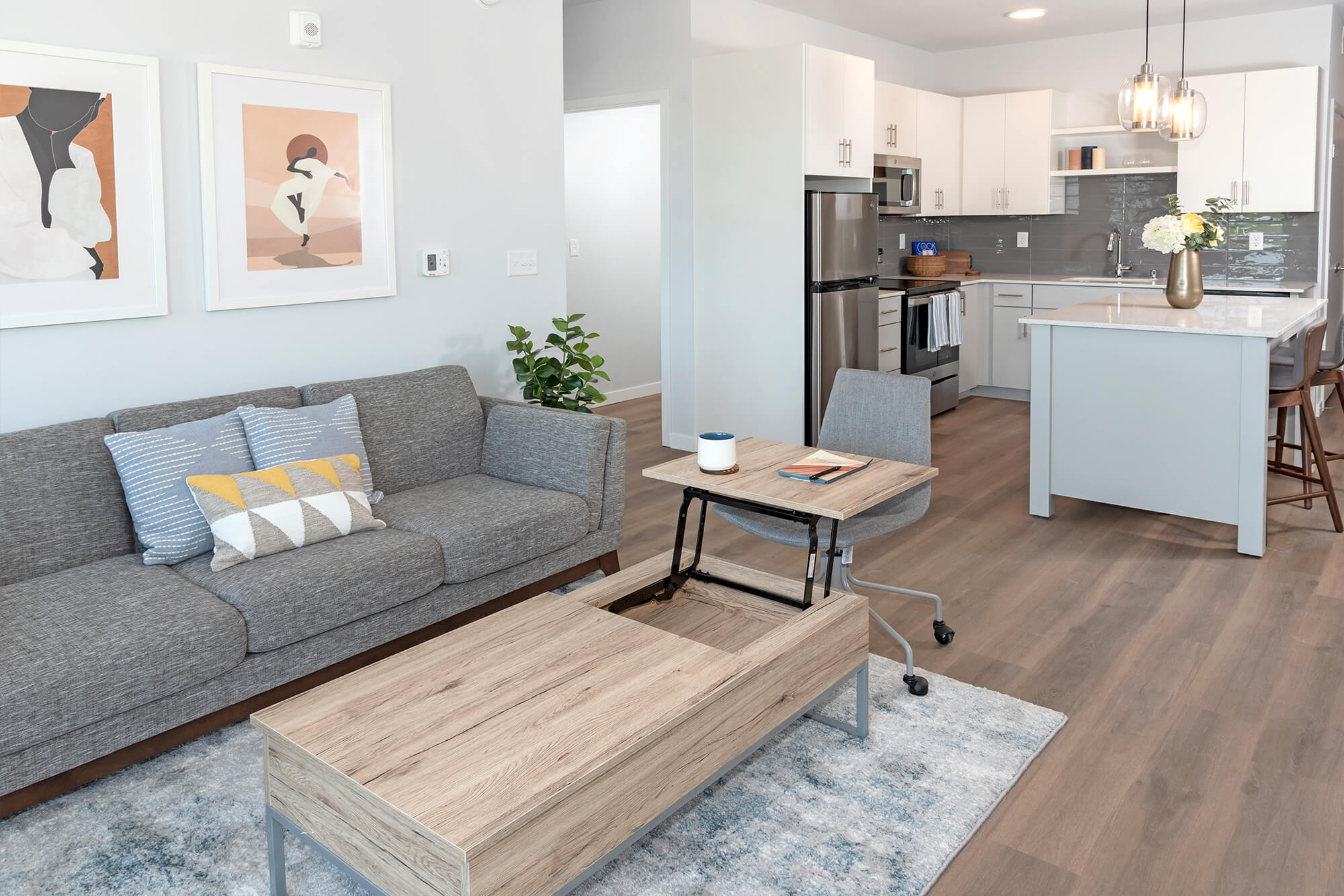 Open-concept apartment living room and kitchen with a sofa, coffee table, and island seating.