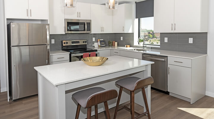 Everlake apartment kitchen with white cabinetry, stainless steel appliances, and island seating