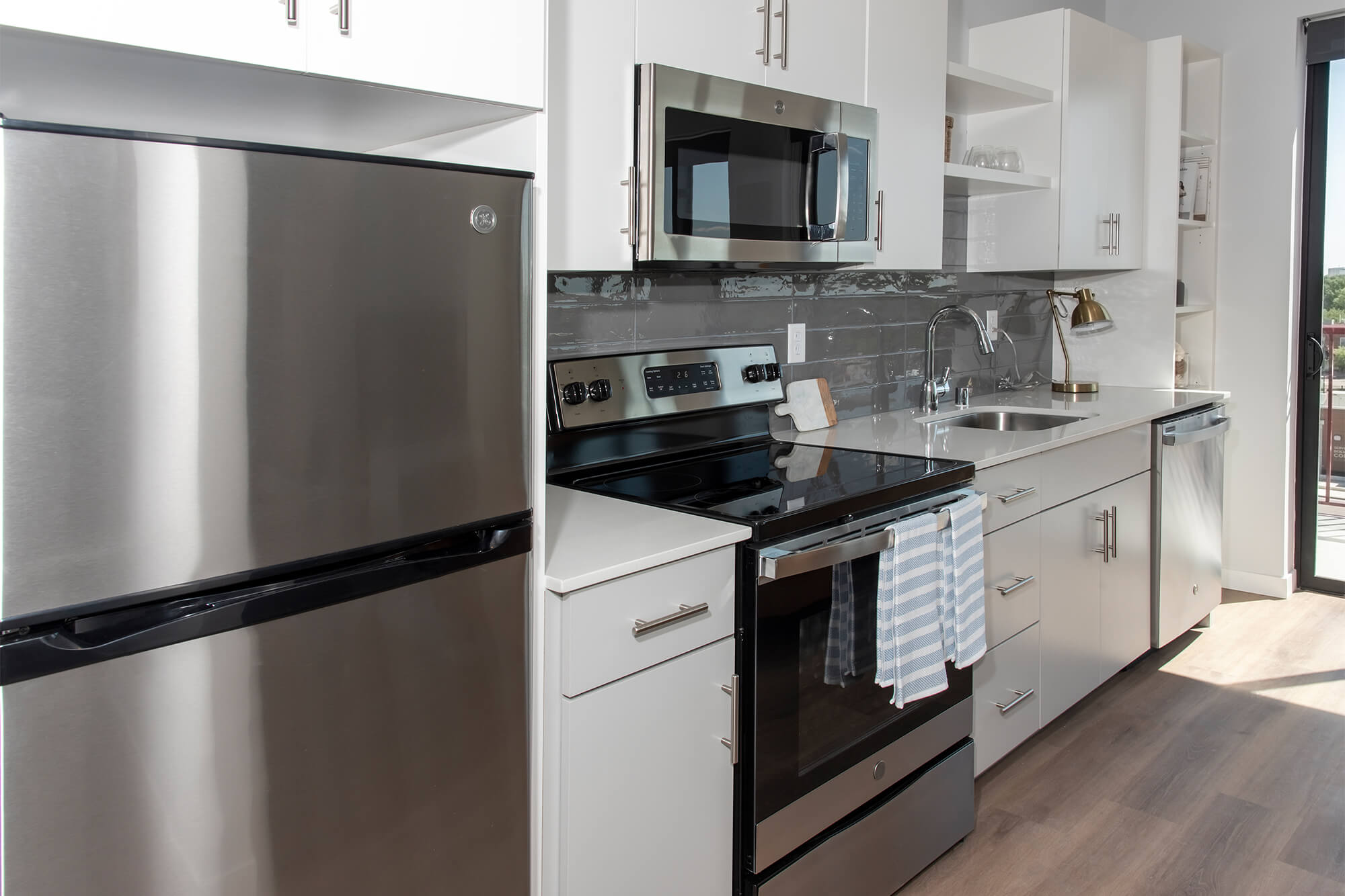 Contemporary kitchen with stainless steel appliances, gray backsplash, and white cabinetry.