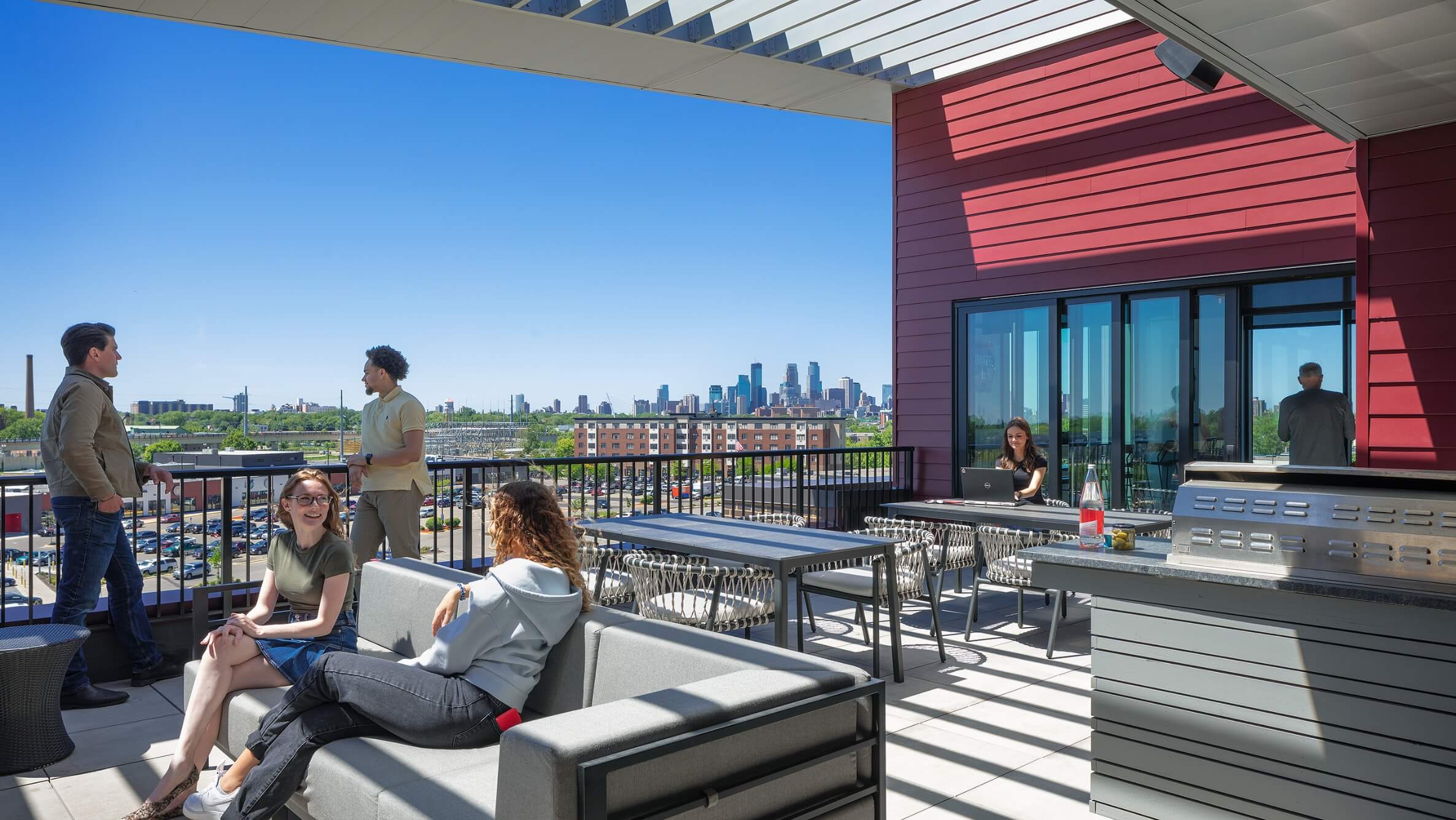 A group of people socializing on the deck at Everlake Apartments with the Minneapolis skyline in the background,