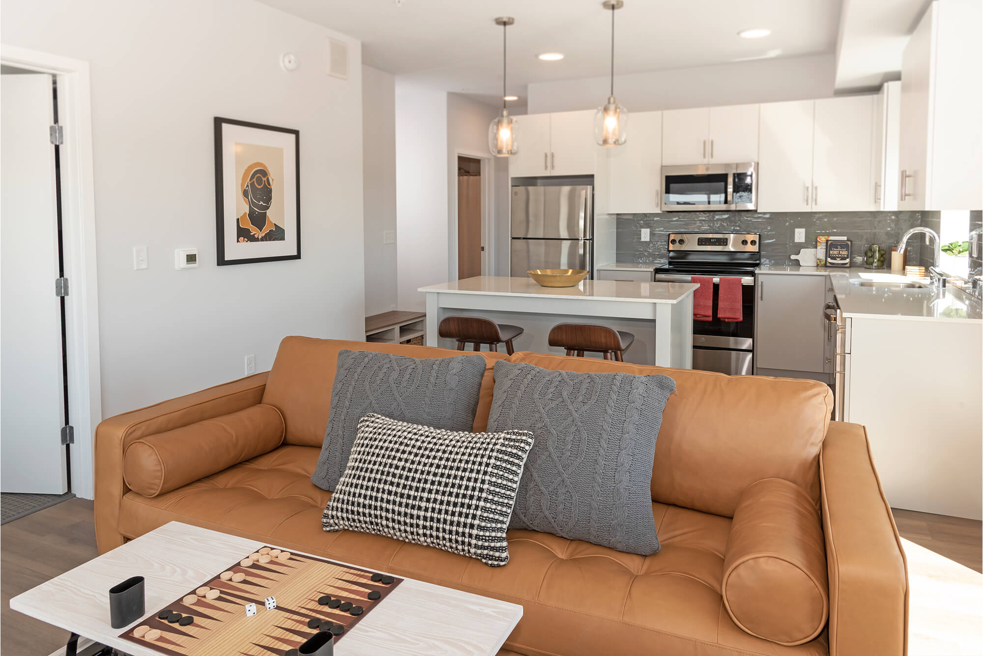 Apartment living room with leather sofa, coffee table, and kitchen in the background.