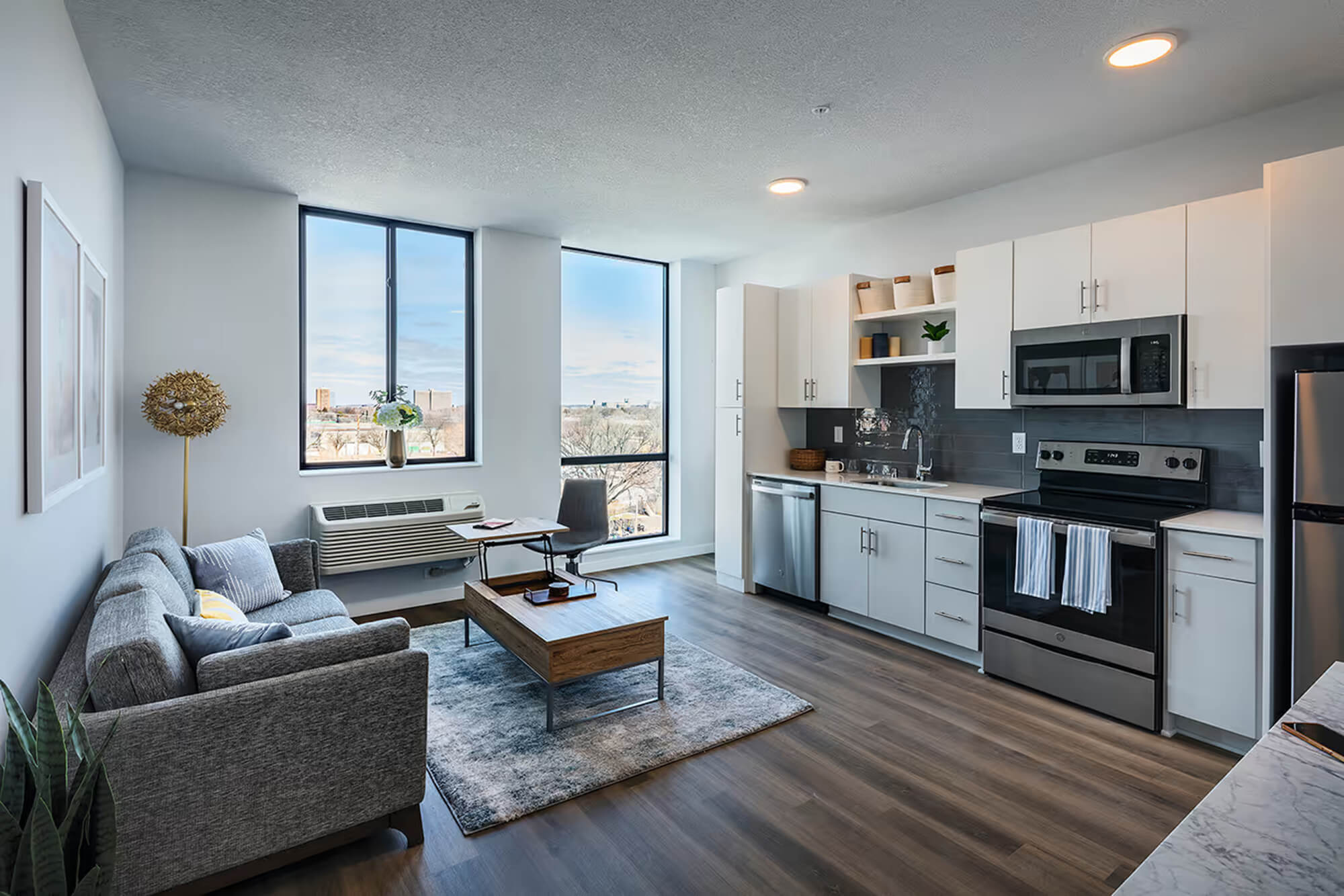 Open studio apartment with kitchen, living area, and large windows