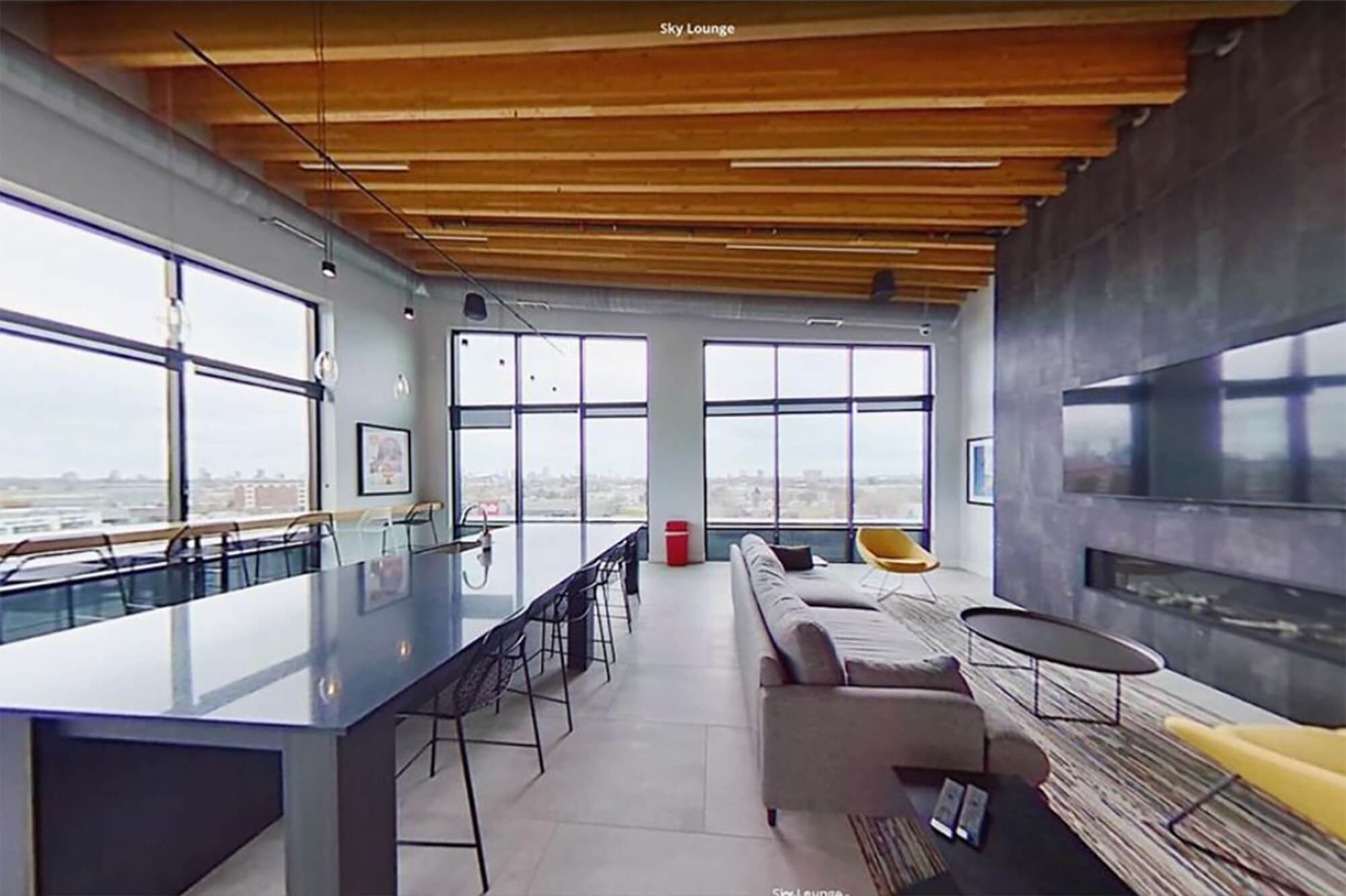 Virtual tour view of the sky lounge with fireplace, seating, and large windows