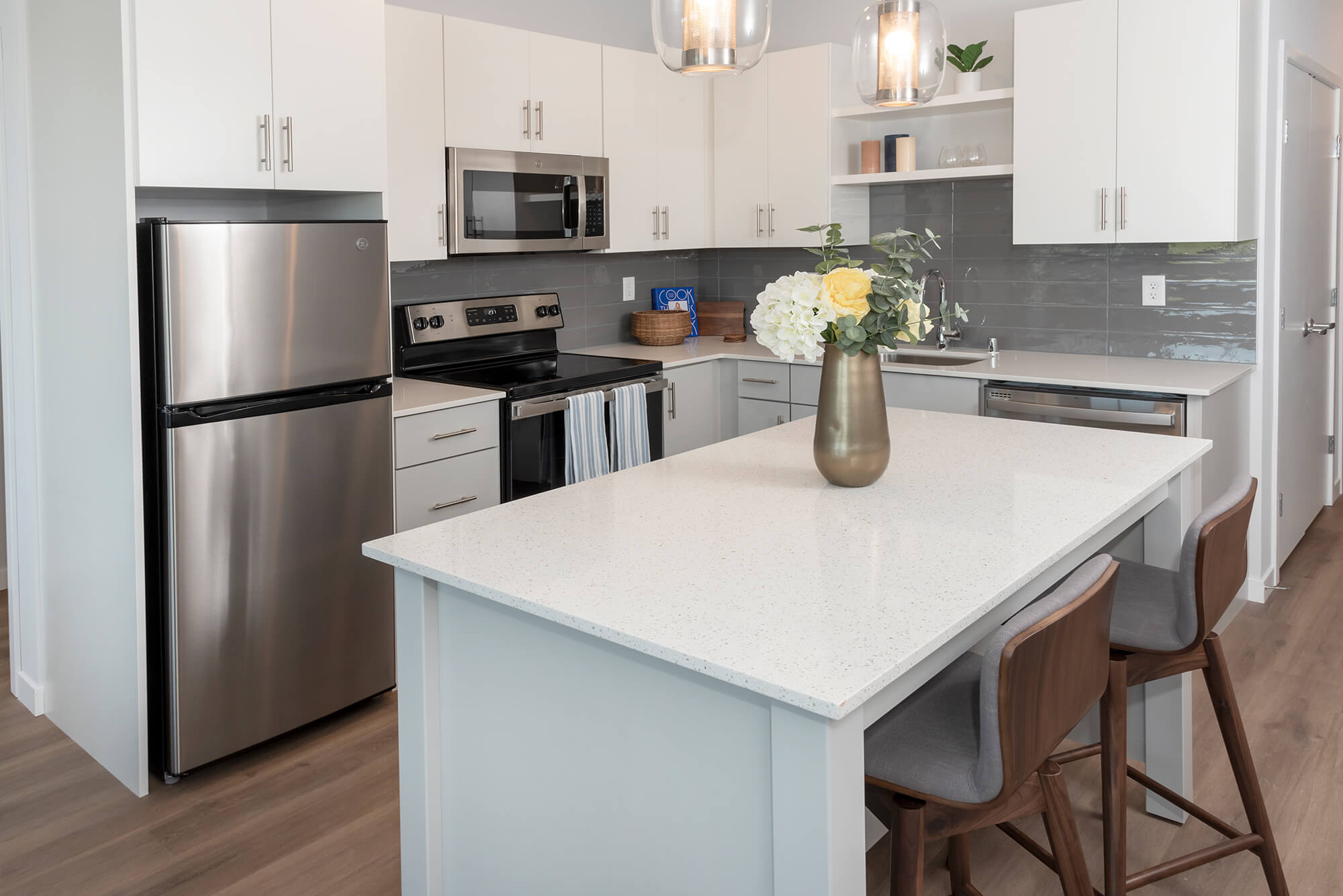 Contemporary kitchen with a large island, white cabinetry, stainless steel appliances, and pendant lighting.