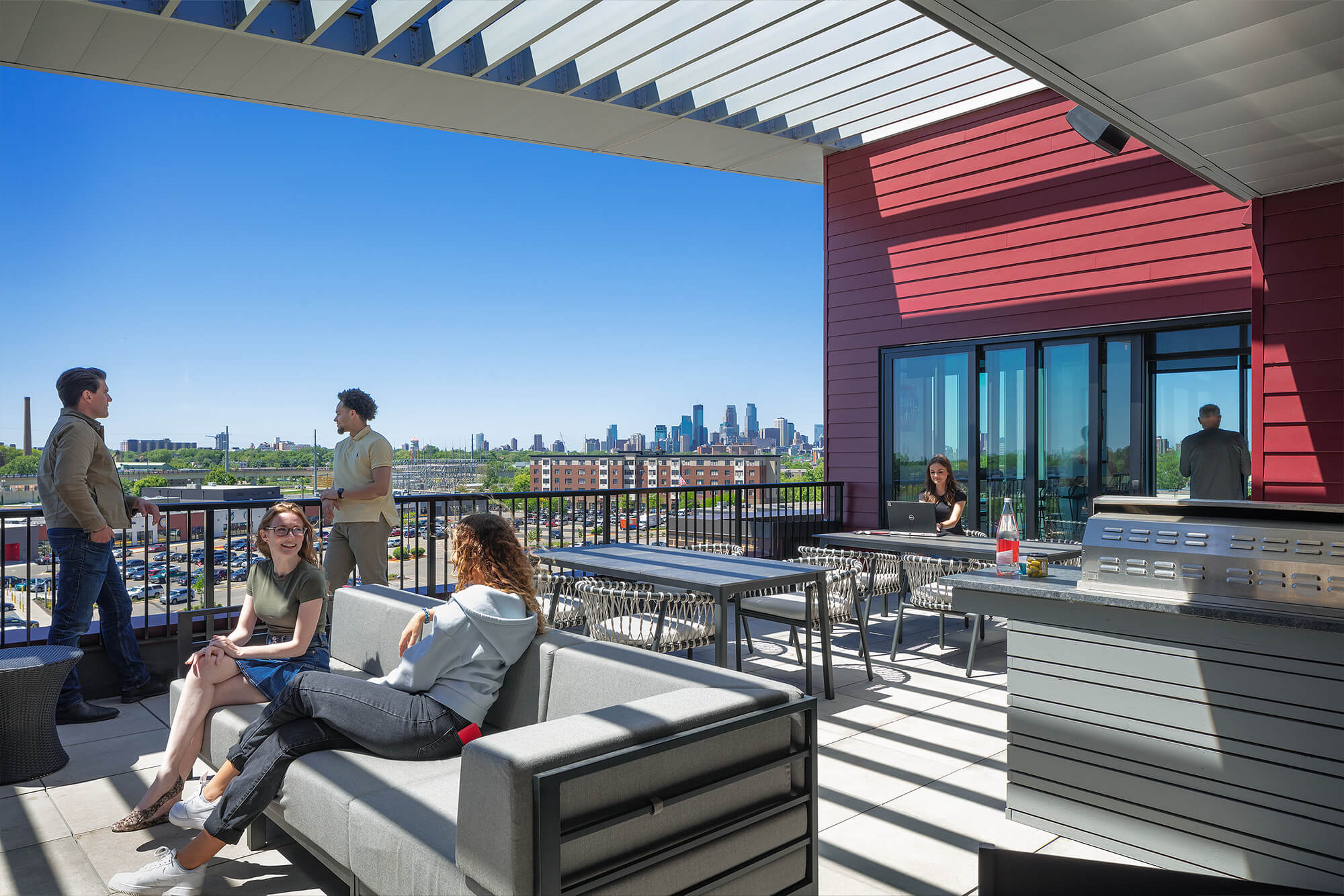 Rooftop patio with lounge seating, dining tables, grilling area, and skyline views.